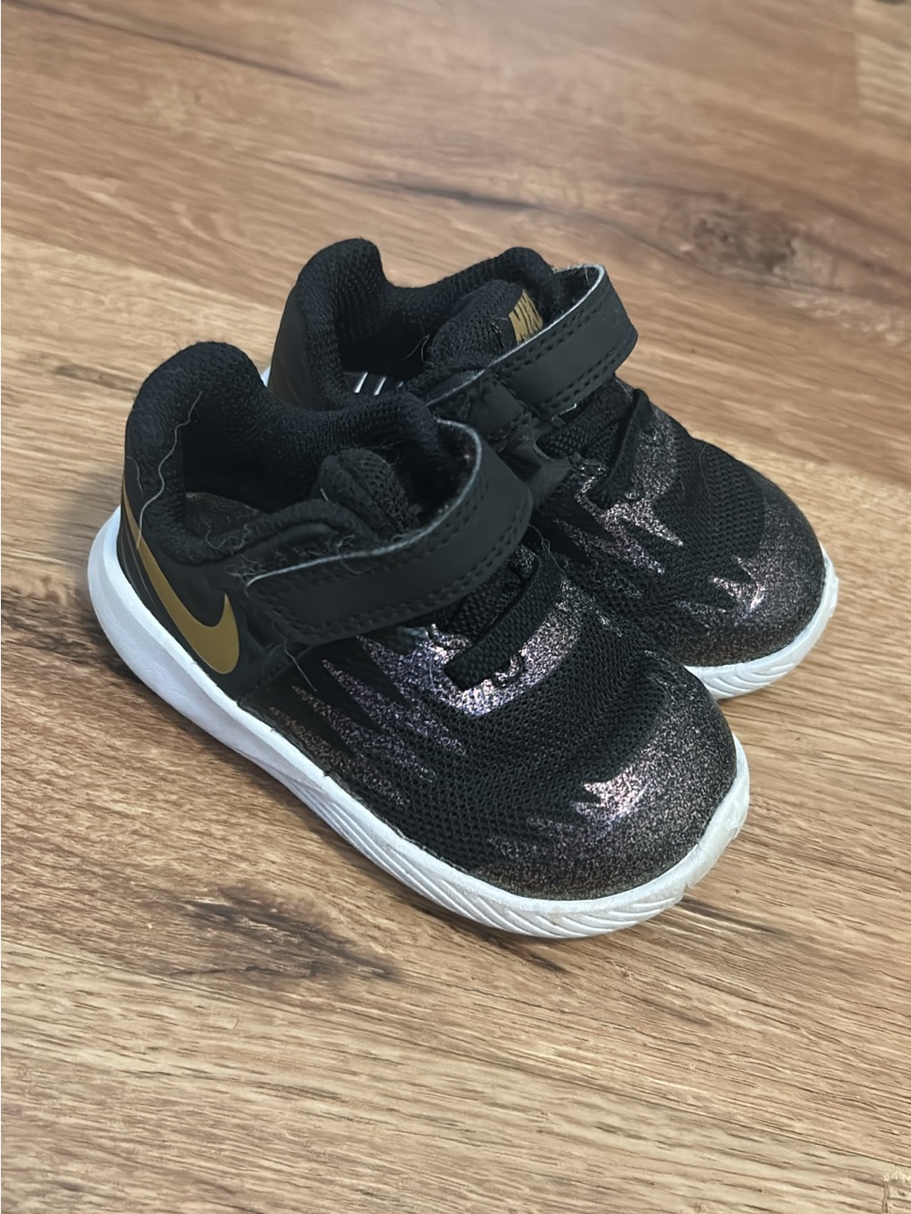 Nike Kids Black Sneakers with Gold Swoosh and Sparkle Accent